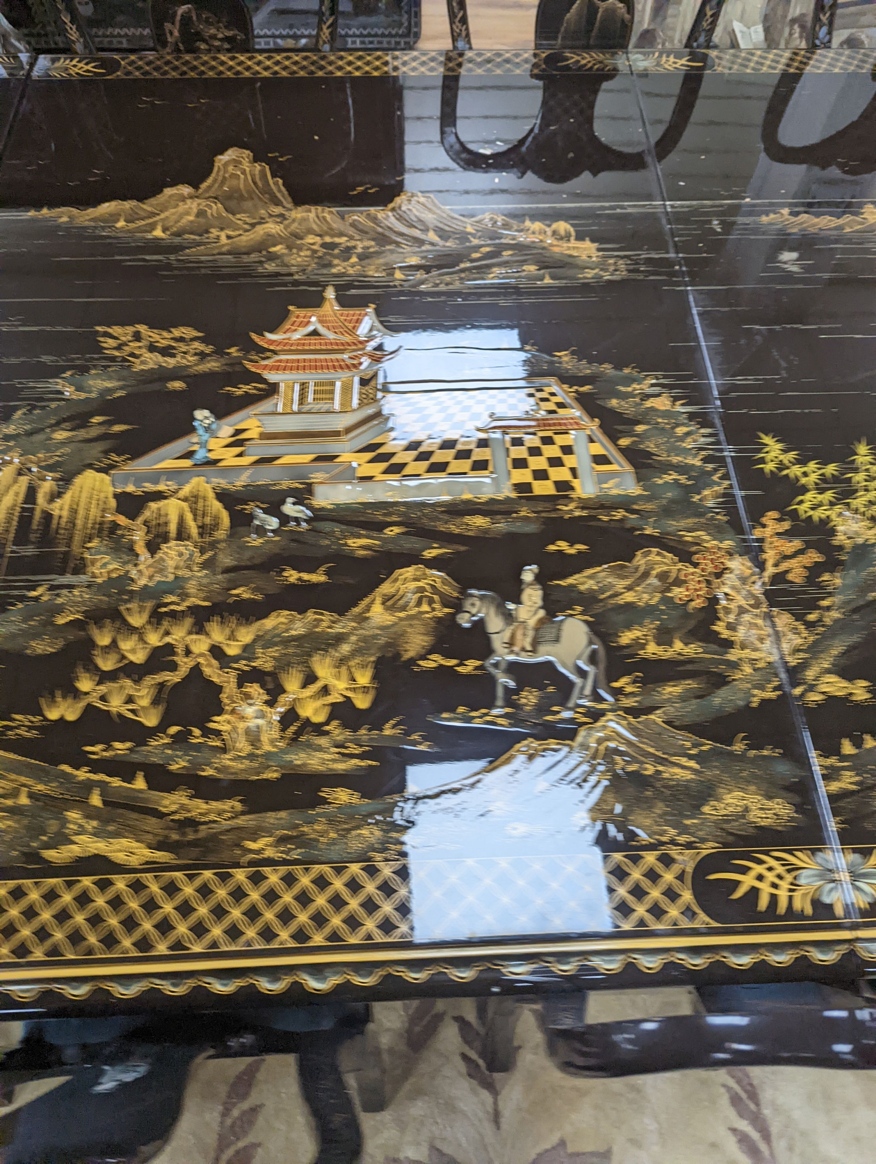 A Chinese lacquer decorated dining table and 12 chairs. Length -277cm, Depth- 120cm, Height - 74cm.